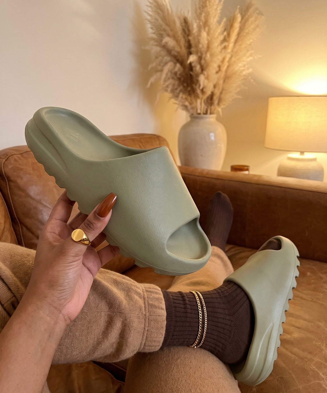 Sage Cloud Slides on a leather sofa